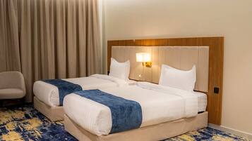 A hotel room with a large bed, a chair, and a patterned carpet.