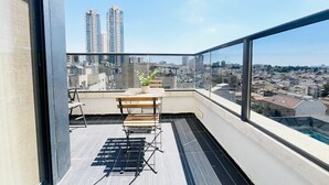 Un balcon avec une table, des chaises et un pot de fleurs.