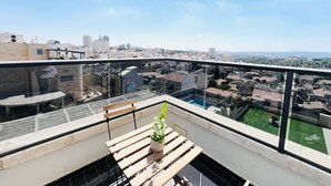 Une terrasse sur le toit offrant une vue sur le paysage urbain, avec une piscine et un pot de fleurs.