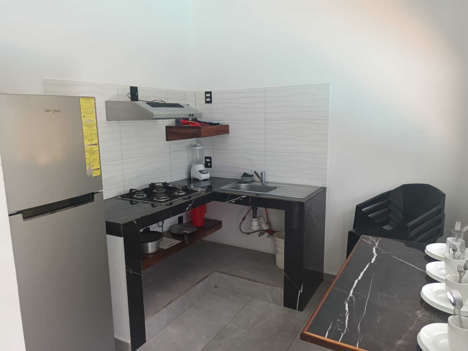 A compact kitchen with a gas stove, sink, and a refrigerator.