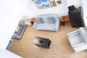 A modern living room with a grey sofa, a white armchair, a coffee table, and a dark wooden cabinet. - Stylish Duplex in the Heart of Walsall (Walsall)