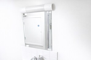 A bathroom with a white tiled wall, a white toilet, and a white sink with a faucet. - Stylish Duplex in the Heart of Walsall (Walsall)