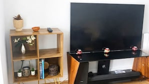 Ein Wohnzimmer mit einem Holz-TV-Möbel, einem Flachbildfernseher und einem Regal mit Dekoration.
