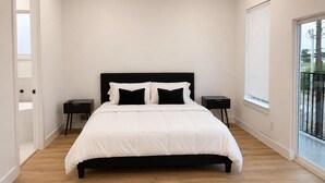 A bedroom with a bed, two bedside tables, a window with blinds, and a door. - Delightful 3-bedroom house with AC in vibrant Houston (Houston)