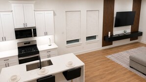 A modern kitchen with white cabinetry, a built-in oven, and a dining area with a white table and black chairs. - Delightful 3-bedroom house with AC in vibrant Houston (Houston)