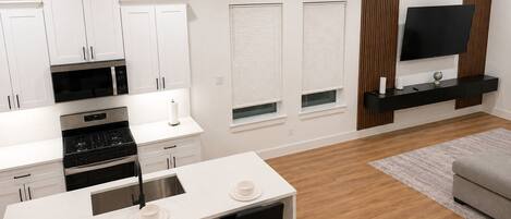A modern kitchen with white cabinetry, a built-in oven, and a dining area with a white table and black chairs.