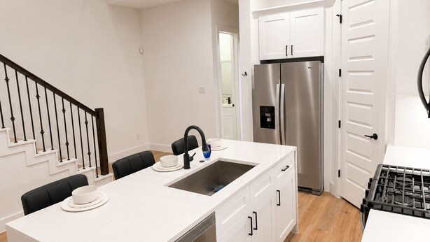 A modern kitchen with white cabinetry, a stainless steel refrigerator, a dishwasher, and a gas stove. - Delightful 3-bedroom house with AC in vibrant Houston (Houston)