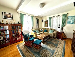 A living room with a sofa, armchairs, a coffee table, a bookshelf, and a rug. - Adorable Venice home in sought after Silver Triangle - walk to everything! (Los Angeles)