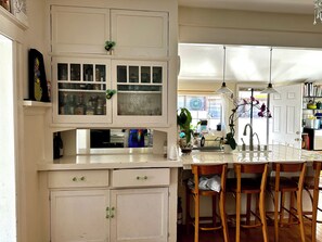 A kitchen with white cabinets, a central island with chairs, and a window with curtains. - Adorable Venice home in sought after Silver Triangle - walk to everything! (Los Angeles)