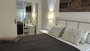 Une chambre à coucher comprenant un lit, des tables de chevet, une armoire et des lampes fixées au mur.