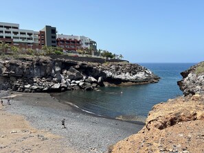 A coastal area with rocky terrain, a beach, and a building with multiple balconies. - Apartment in Playa Paraíso, a 3-minute walk from the beach (CN)