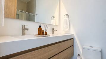 Een moderne badkamer met een wit wastafel, houten opbergmeubel, een grote spiegel en een toilet.