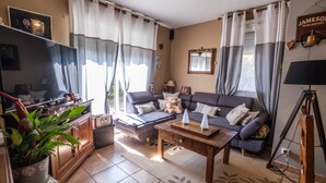 A cozy living room with a sofa, coffee table, and a television. - Alyxia's Villa - LA BASTIDE-PUYLAURENT (LA BASTIDE-PUYLAURENT)