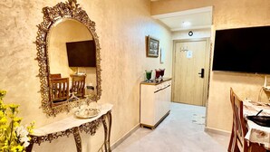 A dining area with a chandelier, a large ornate mirror, and a television. - Elegant family 2br flat, secure 24/7, quiet area (Tangier)