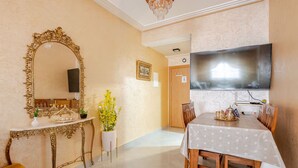 A dining area with a table, chairs, a large mirror, and a television. - Elegant family 2br flat, secure 24/7, quiet area (Tangier)