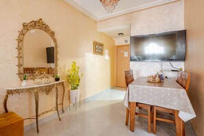 A dining area with a table, chairs, a large mirror, and a television. - Elegant family 2br flat, secure 24/7, quiet area (Tangier)