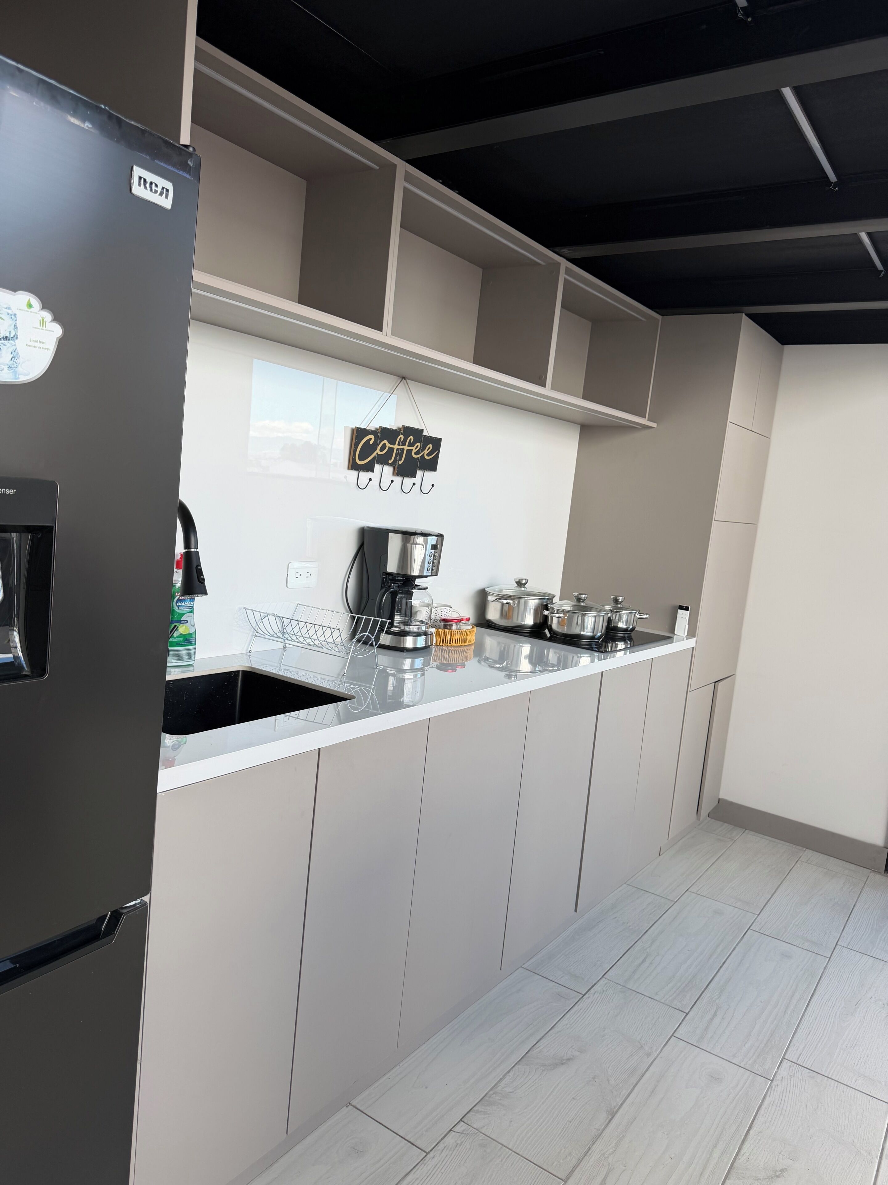 A modern kitchen with a built-in refrigerator, a coffee machine, and a sign indicating a coffee area.