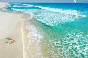 A beach with clear turquoise water, a sandy shore, and a sailboat in the distance. - Coastal Comfort Just a 3-Minute Walk to Navarre Beach | Pool | Sleeps 6 (Navarre)