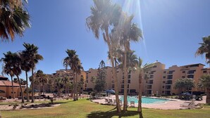 En resort med pool, palmer og en klar blå himmel.