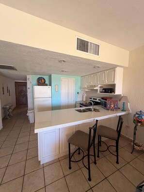 A kitchen with a central island, white cabinets, a sink, and a stove. - Princesa Resort D-105 A Ground Floor Ocean view Condo (Puerto Peñasco)