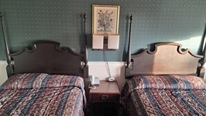 A hotel room with two beds, a bedside table with a telephone, and a framed botanical illustration on the wall. - Southwood Inn  (Selmer)