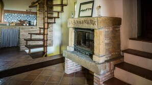 A stone fireplace with a chimney, a wooden staircase, and a tiled floor.