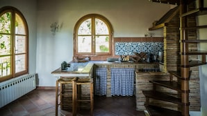 A kitchen with a central island, a wooden staircase, and large windows.