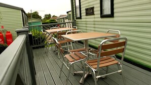 En terrass med metallstolar och -bord, ett räcke och en byggnad med en skylt som visar texten ”VOGUE”.