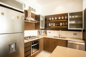 A modern kitchen with stainless steel appliances, wooden cabinets, and built-in shelves. - Beautiful 2 bed 2 bath
Penthouse in the heart of the Romantic Zone (Puerto Vallarta)
