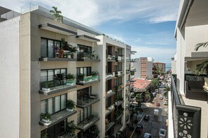 Ein mehrstöckiges Gebäude mit Balkonen, großen Fenstern und Blick auf die Straße und das Meer.