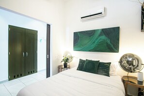 A bedroom with a bed, a wall-mounted air conditioner, a green abstract painting, and a potted plant. - Beautiful 2 bed 2 bath
Penthouse in the heart of the Romantic Zone (Puerto Vallarta)