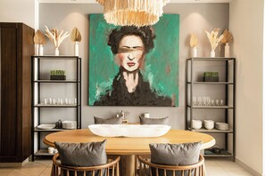 A dining area with a round wooden table, two chairs, a central white bowl, and a painting above. - Beautiful 2 bed 2 bath
Penthouse in the heart of the Romantic Zone (Puerto Vallarta)