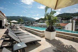 Ein Poolbereich auf dem Dach mit Liegestühlen und Blick auf die umliegende Landschaft.
