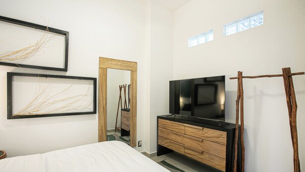 Una camera da letto con un letto, una TV, una cassettiera in legno e opere d'arte alle pareti.
