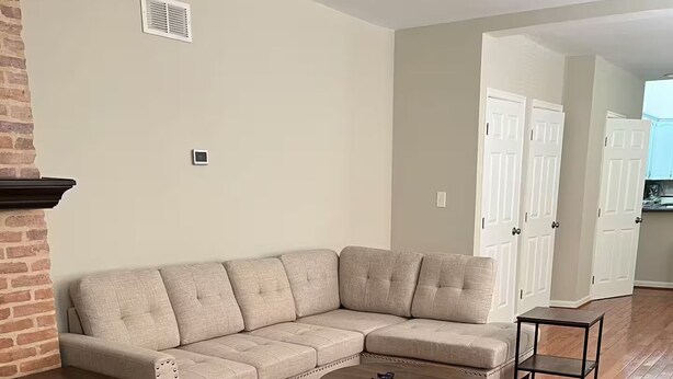 A living room with a sectional sofa, two coffee tables, and a brick accent wall. - Spacious 3-bedroom Townhome in Superb Baltimore Location with AC and Comfort (Baltimore)