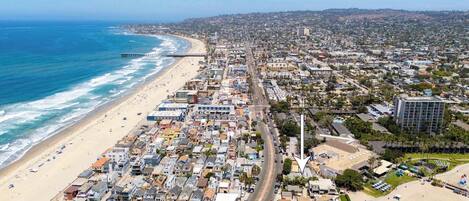 Un paysage urbain côtier comprenant une plage, une zone résidentielle densément peuplée et un phare imposant.