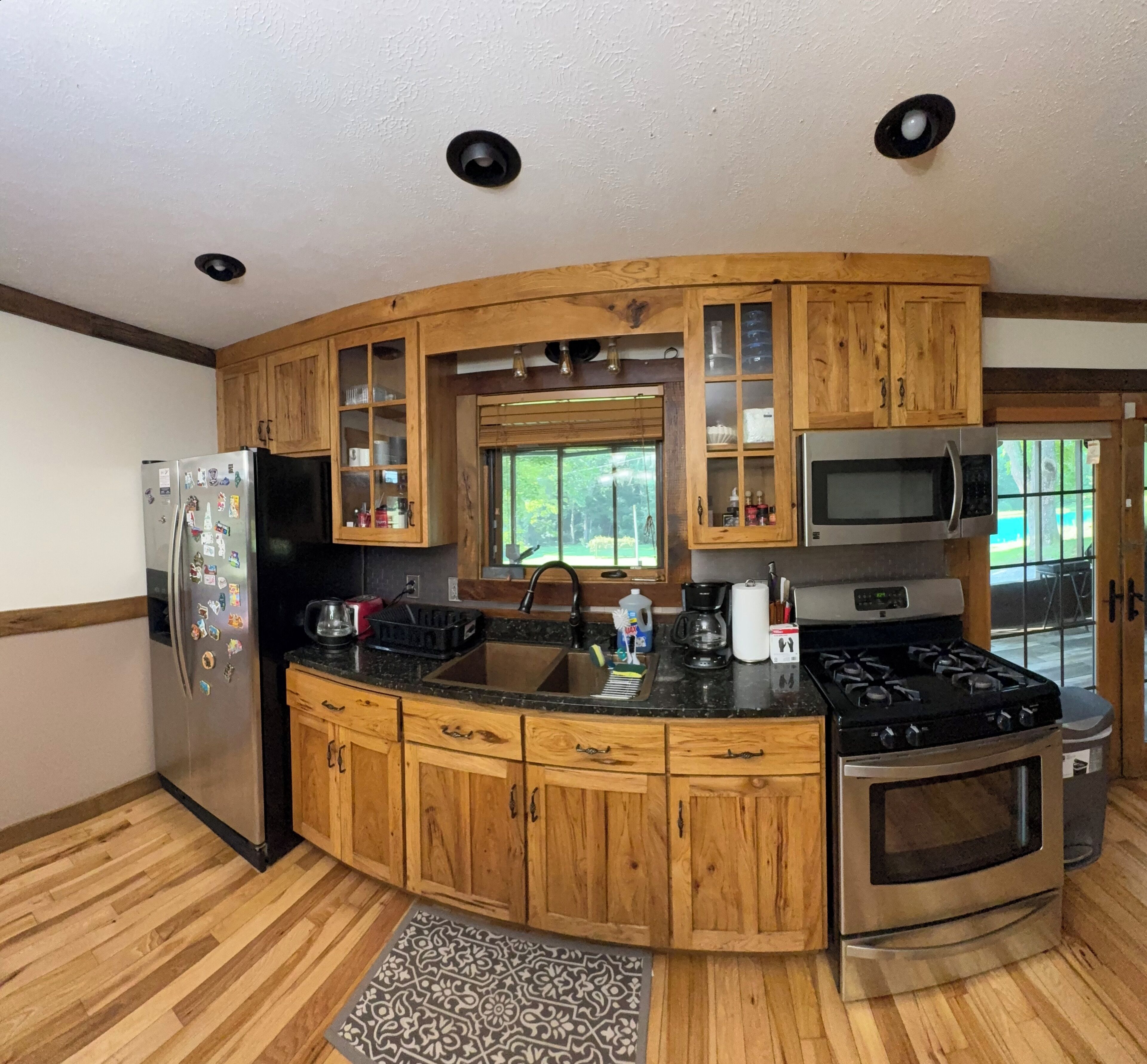 Une cuisine avec des meubles de rangement en bois, un réfrigérateur, un four à micro-ondes et une cuisinière.