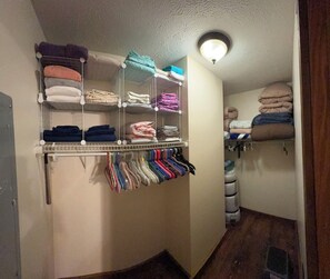 A storage closet with shelves for folded towels and a rack for hanging clothes. - Welcome Dona Catalina Farm House a quiet and spacious home in Tell City IN. (Tell City)