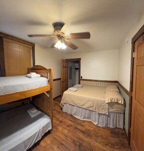 A room with two bunk beds, a ceiling fan, and a door leading to a hallway. - Welcome Dona Catalina Farm House a quiet and spacious home in Tell City IN. (Tell City)