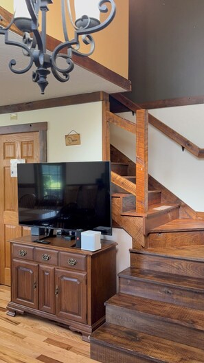 Una escalera con barandillas de madera y un televisor de pantalla plana sobre un mueble de madera.