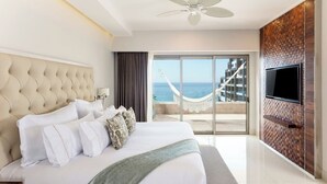 A hotel room with a large bed, a television, a view of the sea, and a hammock outside. - Garza Blanca Resort & Spa Los Cabos 2-Bedroom Hotel Suite (Cabo San Lucas)
