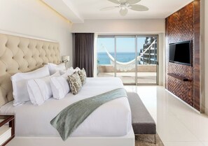 A hotel room with a large bed, a television, a view of the sea, and a hammock outside. - Garza Blanca Resort & Spa Los Cabos 2-Bedroom Hotel Suite (Cabo San Lucas)