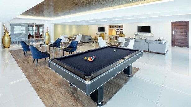 A modern living room with a pool table, sofas, and a dining area. - Garza Blanca Resort & Spa Los Cabos 2-Bedroom Hotel Suite (Cabo San Lucas)