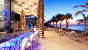 An outdoor bar area with a view of the ocean, seating arrangements, and a modern architectural design. - Garza Blanca Resort & Spa Los Cabos 2-Bedroom Hotel Suite (Cabo San Lucas)