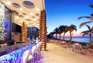 An outdoor bar area with a view of the ocean, seating arrangements, and a modern architectural design. - Garza Blanca Resort & Spa Los Cabos 2-Bedroom Hotel Suite (Cabo San Lucas)