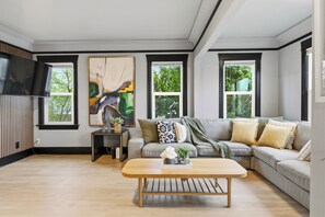 Een moderne woonkamer met een hoekbank, een salontafel en een groot abstract schilderij.