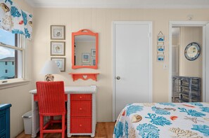 A room with a bed, a desk with a chair, a mirror, and a door. - 412 - Oceanfront w/ gorgeous views and open beach (Nags Head)