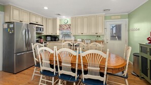 A kitchen with a refrigerator, microwave, and dining table with chairs. - 412 - Oceanfront w/ gorgeous views and open beach (Nags Head)