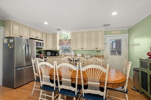 A kitchen with a refrigerator, microwave, and dining table with chairs. - 412 - Oceanfront w/ gorgeous views and open beach (Nags Head)