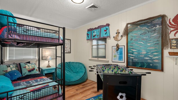 A bunk bed with a blue and red patterned bedspread, a teal bean bag chair, a foosball table, and a wall mural of fish. - 412 - Oceanfront w/ gorgeous views and open beach (Nags Head)